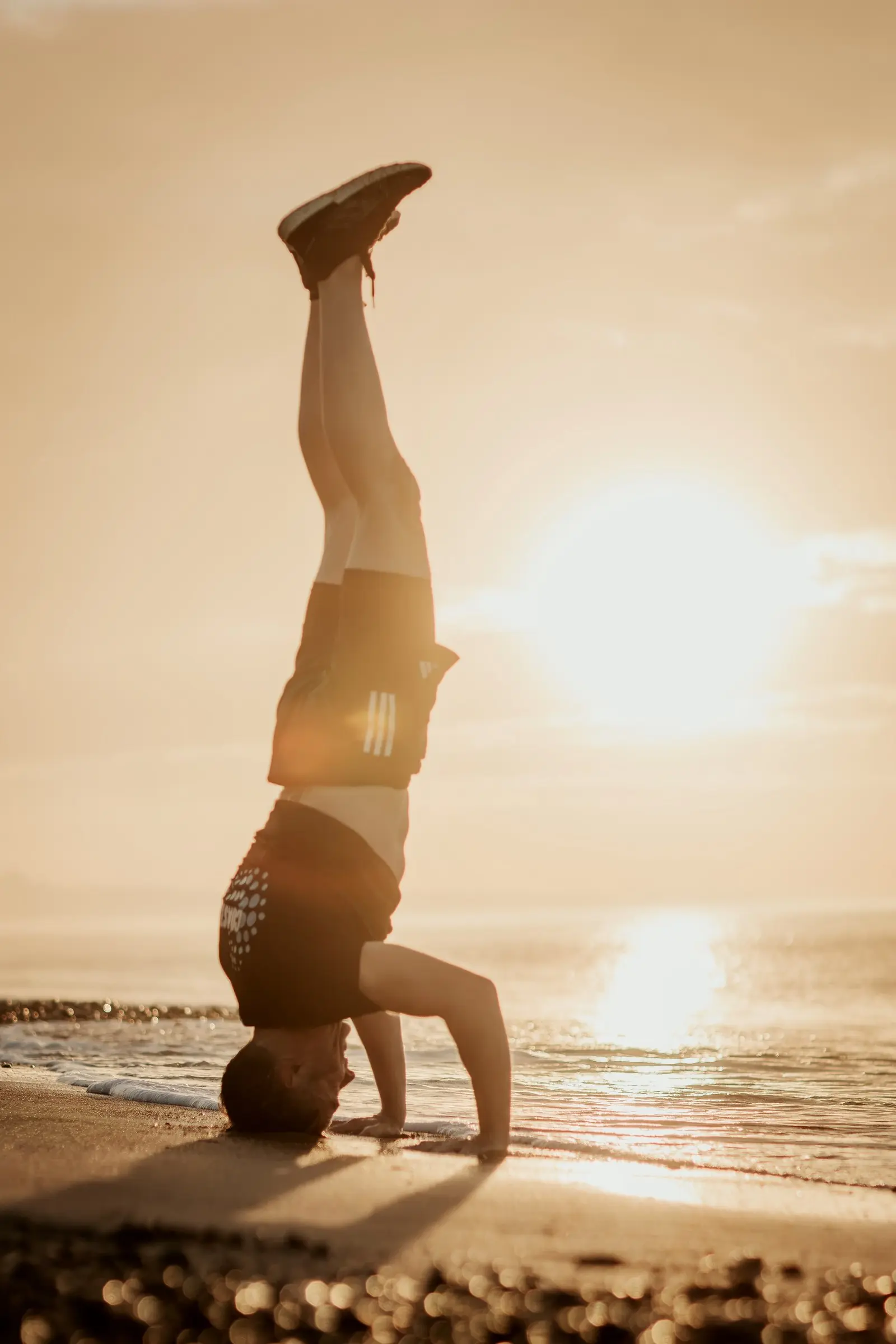 Mark in a headstand on the shingle, the sun low over the sea