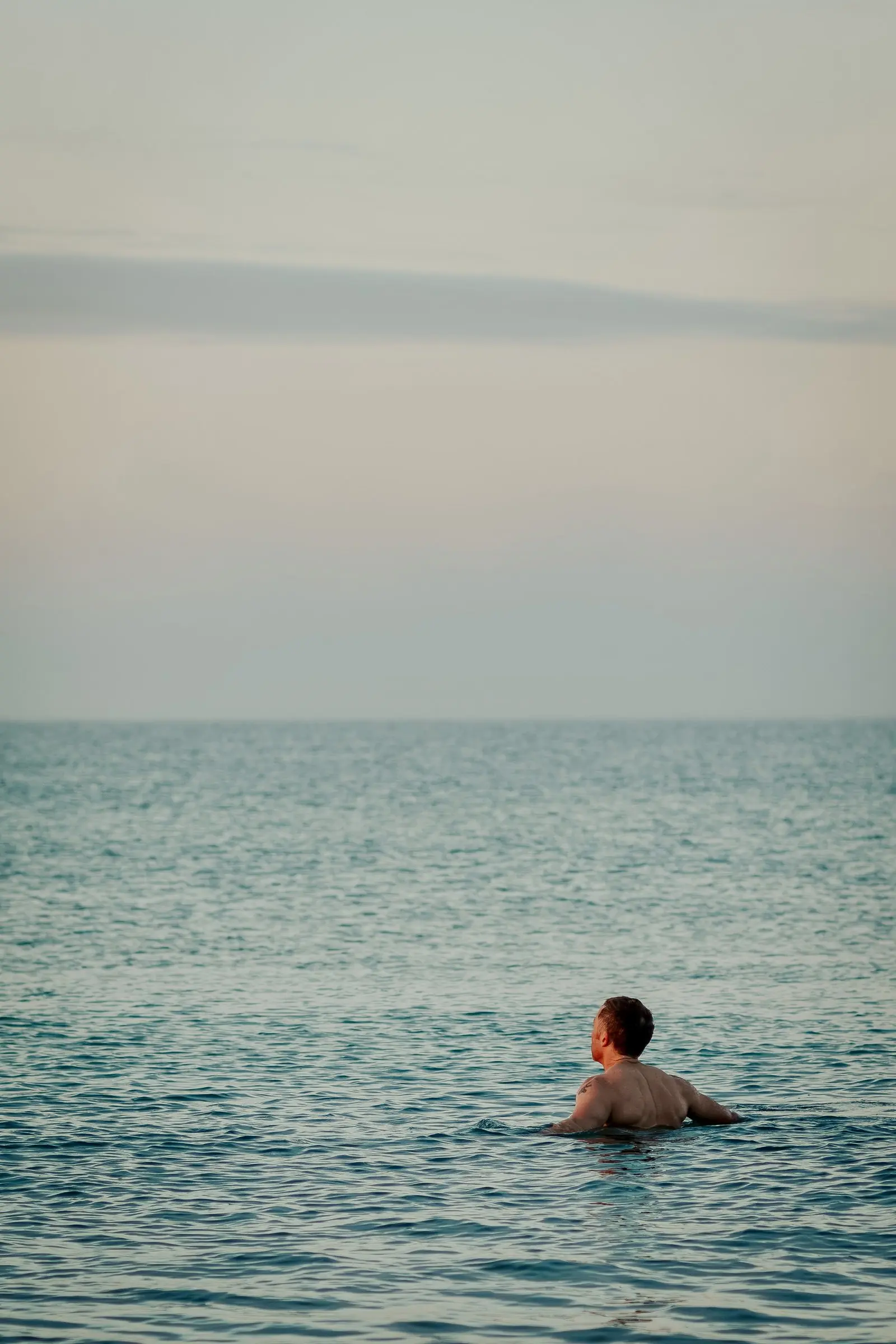 Mark swimming in a calm, grey-blue sea, only his head and shoulders above the water
